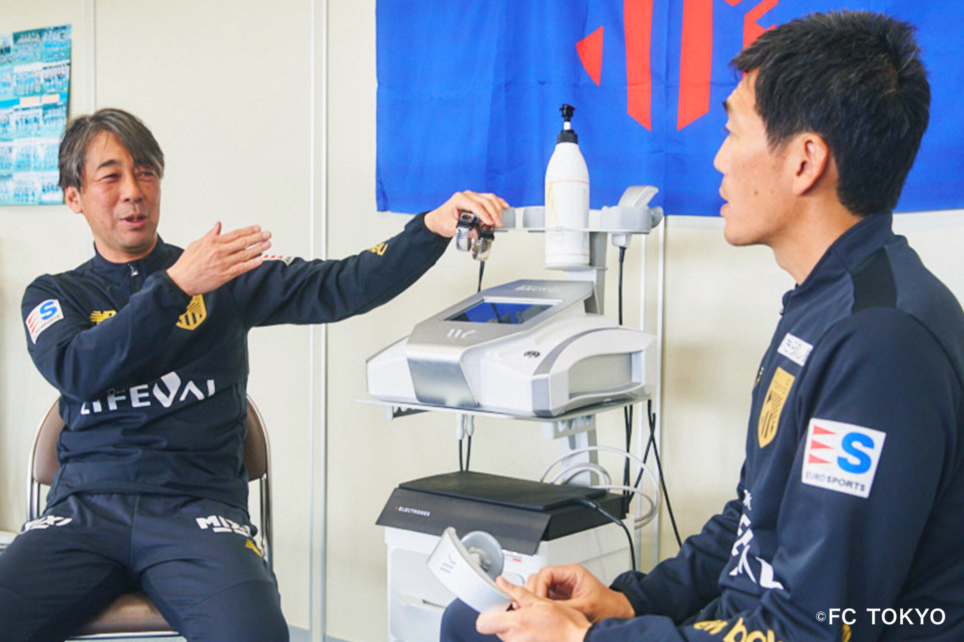 ブレスレット・エレクトロードについて話す青木トレーナーと宮間フィジオセラピストー